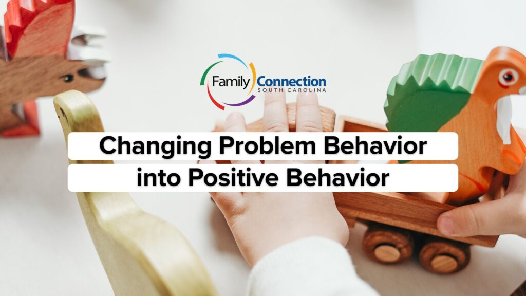 The hands of a young white child playing with a wooden train and wooden dinosaurs. Over all the words Family Connection South Carolina Changing Problem Behavior into Positive Behavior